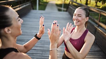 Zwei Sportlerinnen klatschen sich lächelnd ab