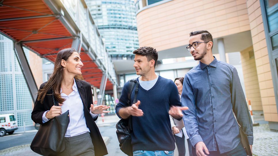 © Mainova/AndreFormer Drei junge Werkstudierende unterhalten sich beim Spaziergang auf dem Gelände der Mainova AG