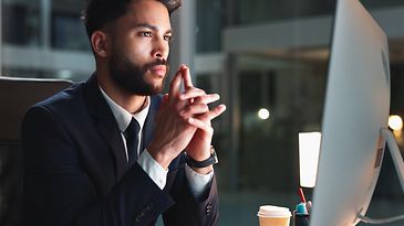 © www.adobestock.com-peopleimages.com Mann sitzt am Schreibtisch und schaut auf einen Monitor
