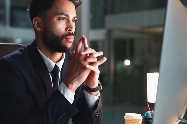 Mann sitzt am Schreibtisch und schaut auf einen Monitor