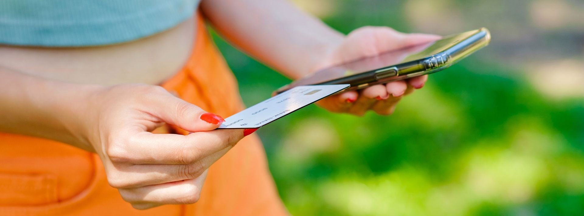 © istock/Burak Guler weibliche Hände halten ein Handy und eine Scheckkarte