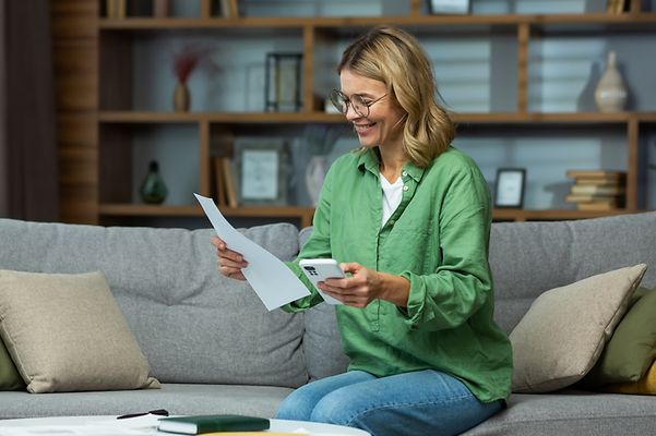 © www.istockphoto.com - Liubomyr Vorona Eine Frau sitzt einen Brief und Taschenrechner in der Hand haltend auf einem Sofa