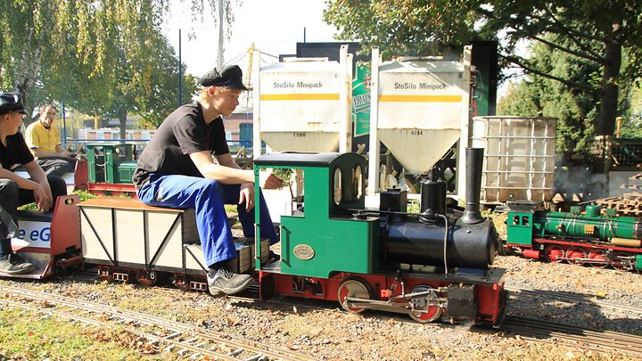 Mann mit Hut sitzt vorgebeugt auf kleiner Dampflokomotive