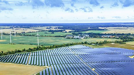 © Mainova/DennisMöbus Großer Solarpark mit Windrädern in weiter Landschaft – Symbol für erneuerbare Energie und nachhaltige Stromerzeugung.