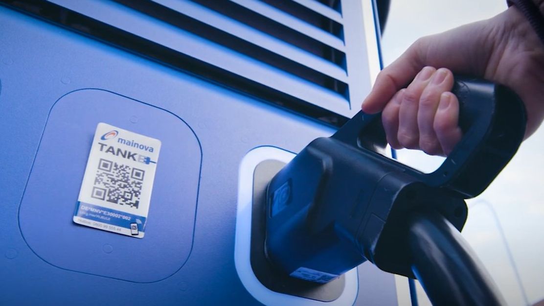 © Mainova Eine Hand führt das Ladekabel zum Elektroauto