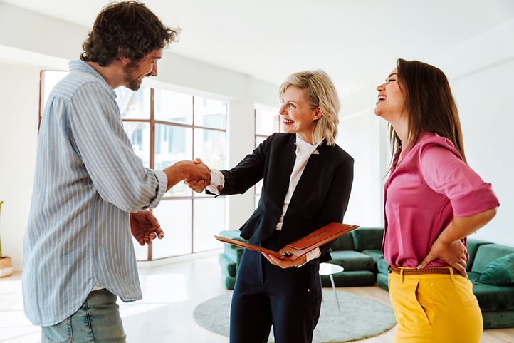 Vermieterin reicht neuem Mieter die Hand, daneben steht die neue Mieterin
