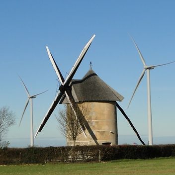 © Mainova Mühle, an der Rotorblätter eines Windrads befestigt sind. Im Hintergrund moderne Windräder