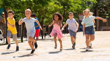 Kinder rennen glücklich auf einem Weg zwischen Bäumen