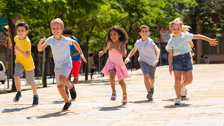 Kinder rennen glücklich auf einem Weg zwischen Bäumen
