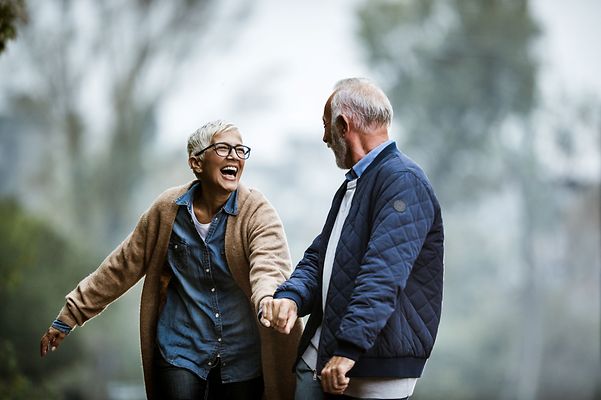 Älteres Ehepaar hält sich beim Spaziergang im Grünen an den Händen