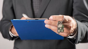 © www.istock.com - abioBalbi Eine Hand hält ein Übergabeprotokoll, die andere Hand einen Hausschlüssel