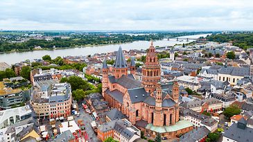 Bild aus der Vogelperspektive zeigt Mainzer Innenstadt, den Mainzer Dom und den Rhein im Hintergrund.
