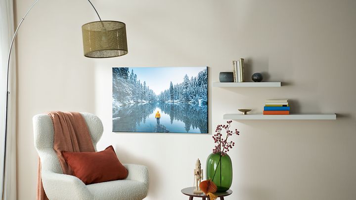 © CEWE Stiftung & Co. KGaA Sessel mit Lampe dahinter und kleinem Tisch und an der Wand ein Foto mit Schneelandschaft