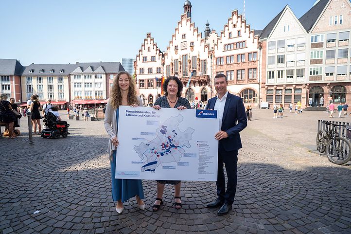 Mainova-Vorstand, Dezernentin für Klima und Stadträtin halten vor dem Frankfurter Römer ein Fernwärmeausbauschild