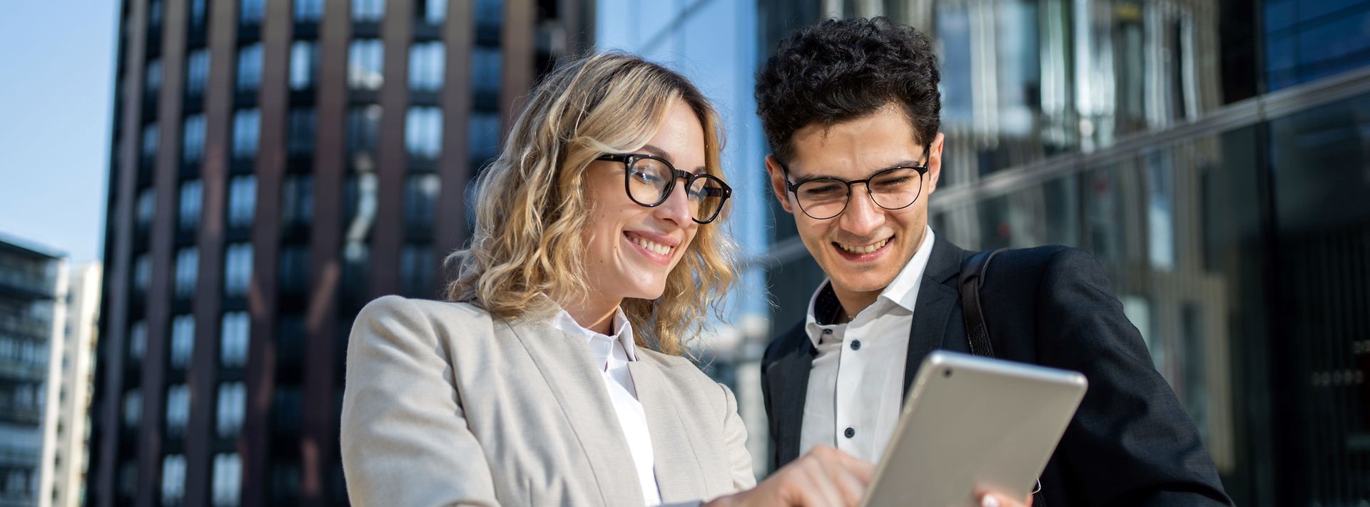 Frau und Mann mittleren Alters schauen auf ein Tablet und lachen