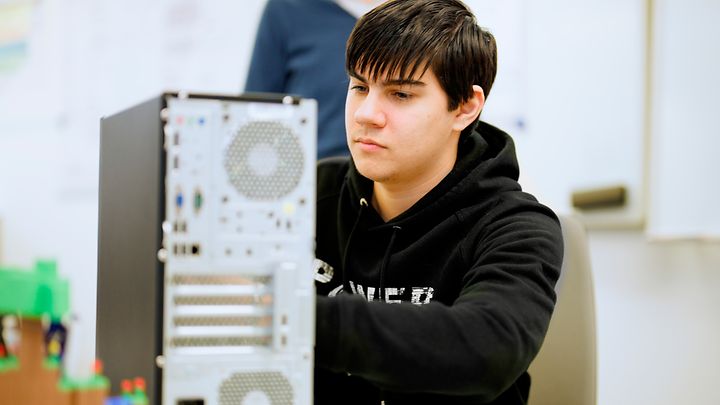  Eine Person arbeitet konzentriert an einem offenen Computergehäuse in einem Technikraum.