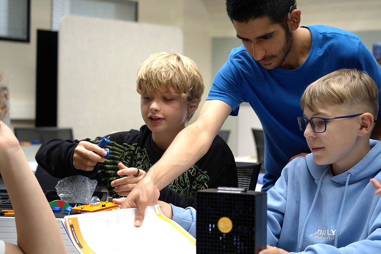 Ein junger Mitarbeiter von Mainova zeigt zwei Schulkindern seine Arbeit