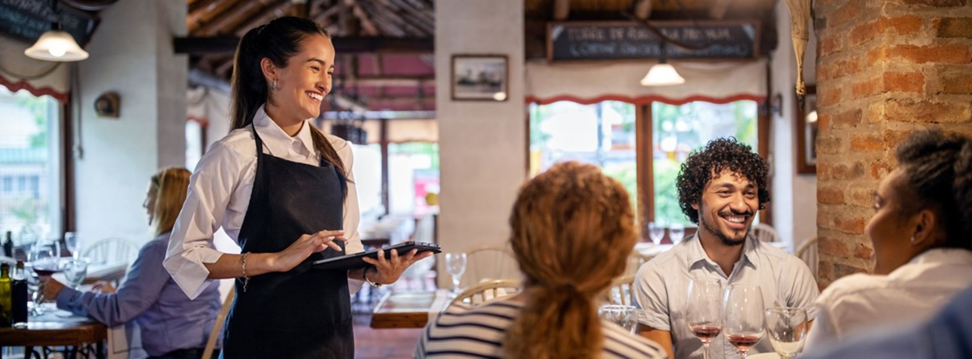 Eine freundliche Kellnerin nimmt die Bestellung der Gäste auf.