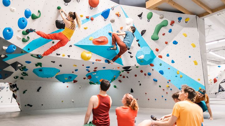 Kletternde Personen in einer Boulderhalle
