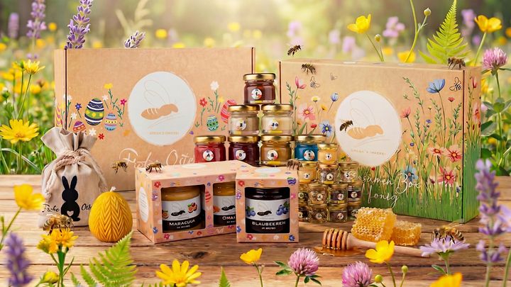 Honig- und Geschenksets in buntem Blumenfeld mit Gläsern, Waben und dekorierten Boxen.