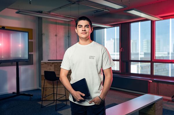 Man mit Notebook in der Hand steht mittig in einem Büro