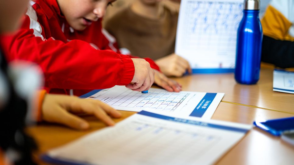 Junge stämpelt in einer Schulumgebung auf einem Papier