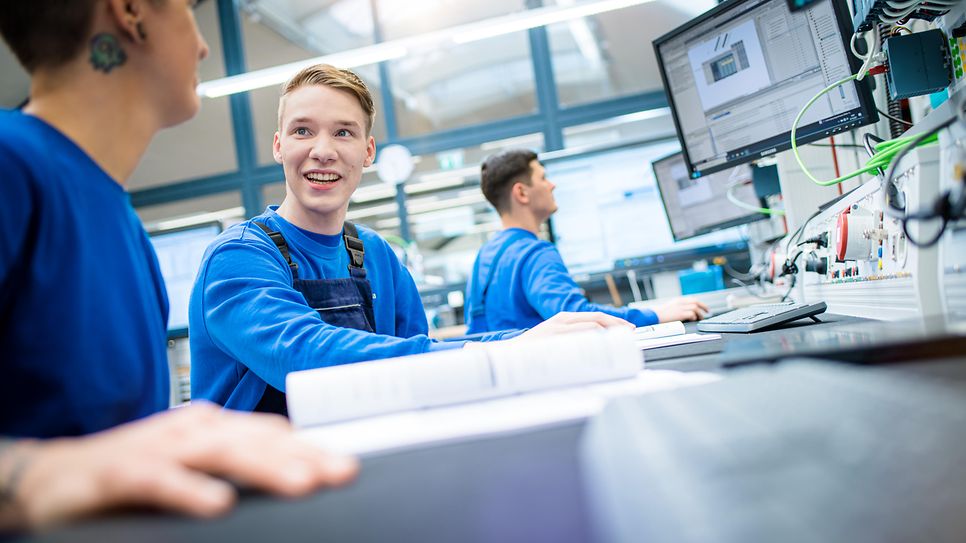 Techniker arbeiten an einer Werkbank mit: Büchern, PCs und Steckern