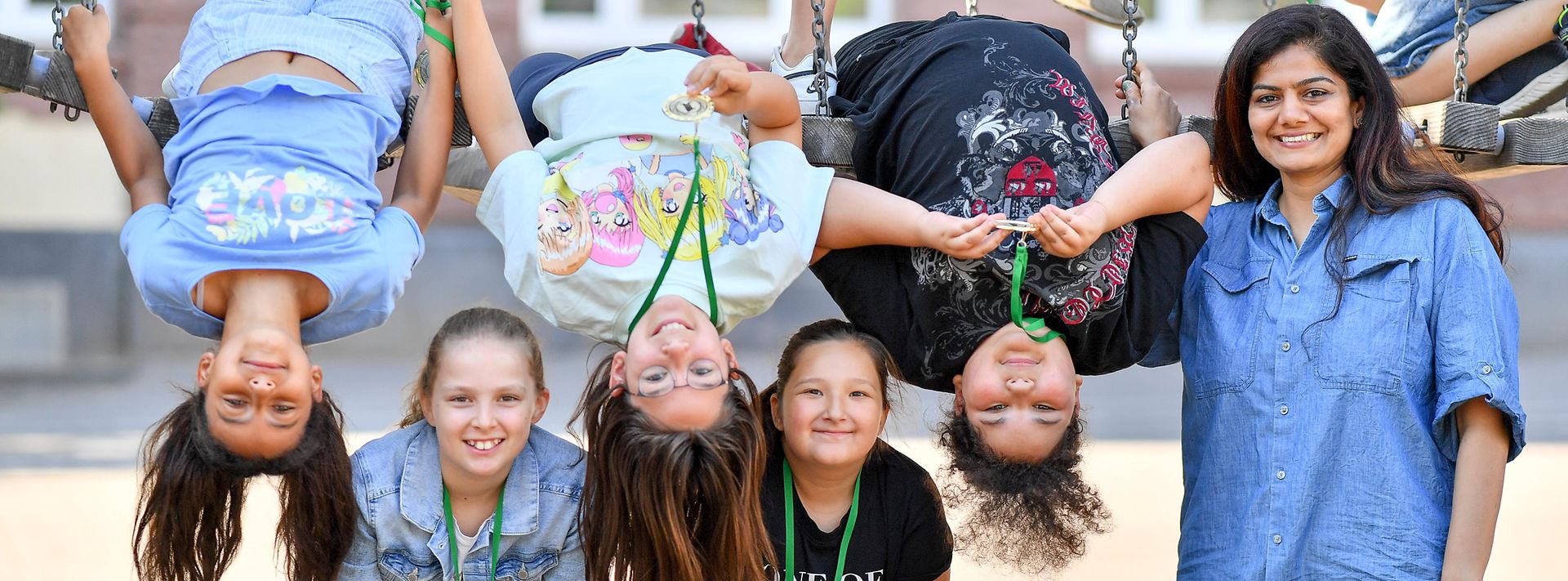 5 Kinder und ein Erwachsener posieren auf einem Spielplatz mit ihren Medallien 