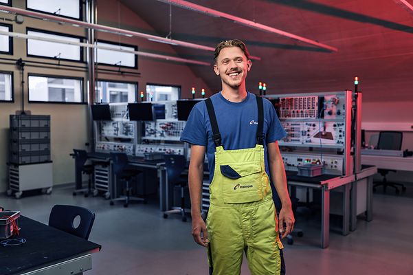 Man steht in einer neuen Latzhose mit verschränkten Armen vor der Kamera