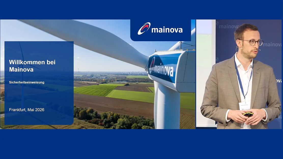  Sicherheitsunterweisung bei Mainova mit Windradmotiv und Vortragendem auf der Bühne.