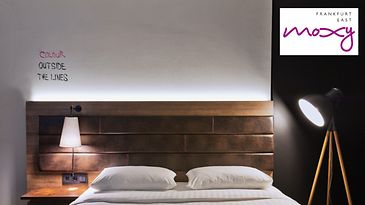 Modernes Hotelzimmer mit Doppelbett, Holzdetails, indirekter Beleuchtung und stilvollen Lampen.