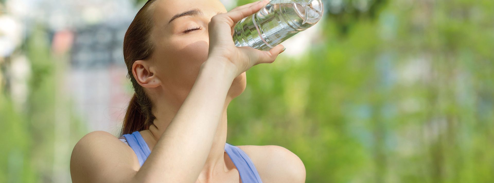 Joggende Frau trinkt aus einer Wasserflasche