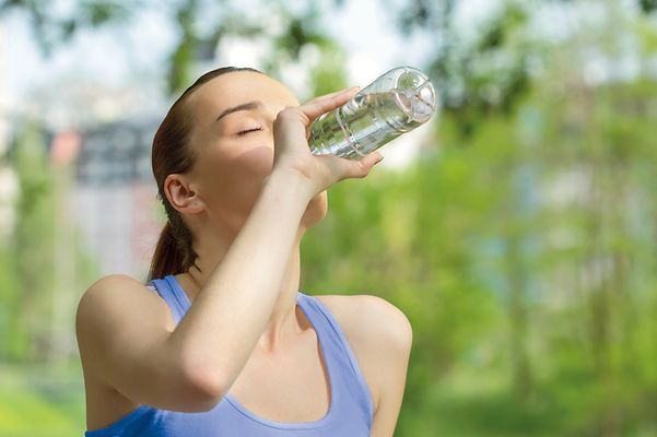 Joggende Frau trinkt aus einer Wasserflasche