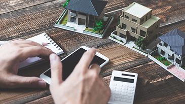 © stock.adobe.com/beeboys Modellhäuser, Smartphone und Taschenrechner