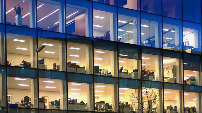 Gebäude mit Glasfassade gibt Blick auf beleuchtete Büroräume