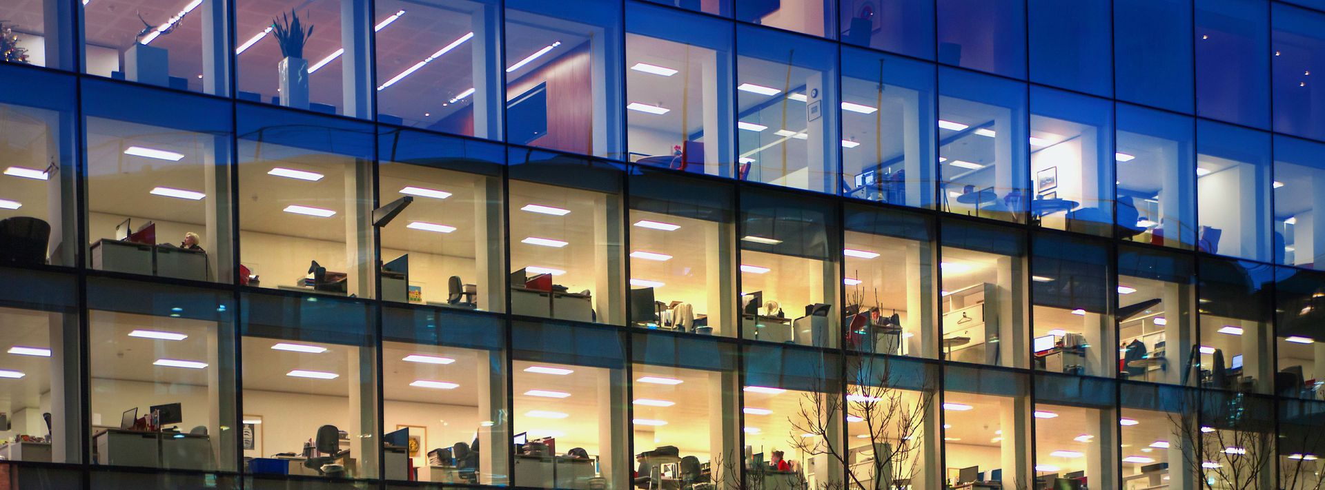 Gebäude mit Glasfassade gibt Blick auf beleuchtete Büroräume