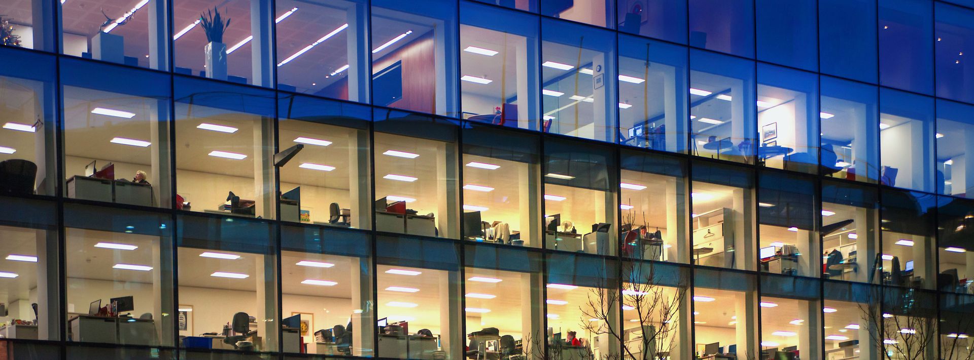 © stock.adobe.com/IRStone Gebäude mit Glasfassade gibt Blick auf beleuchtete Büroräume