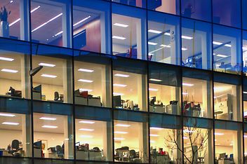 Gebäude mit Glasfassade gibt Blick auf beleuchtete Büroräume