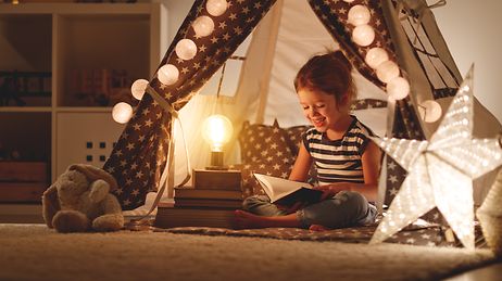 © adobe.stock.com/JenkoAtaman Energiespartipps: Kind liest im Lampenschein