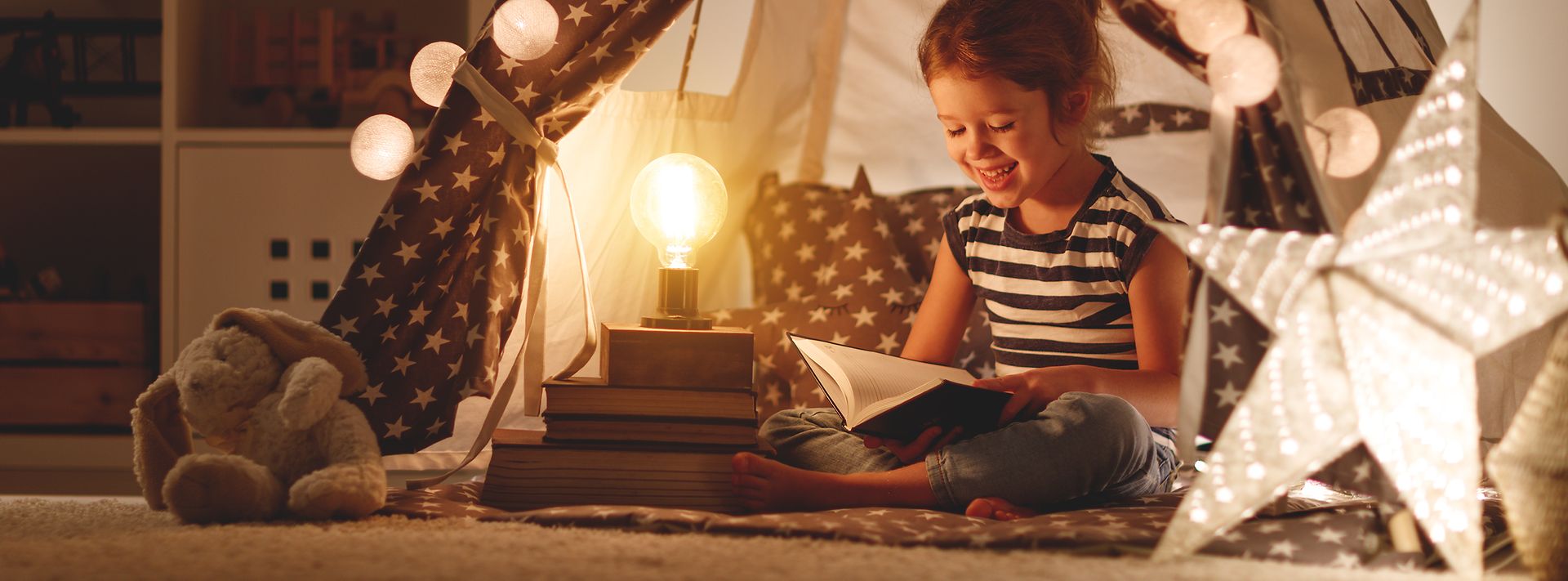 © adobe.stock.com/JenkoAtaman Energiespartipps: Kind liest im Lampenschein