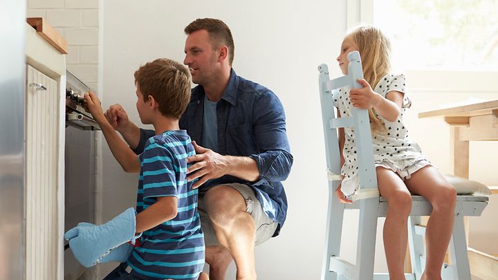 © iStock.com/monkeybusinessimages Ein Vater und seine zwei Kinder prüfen die Herdfunktion