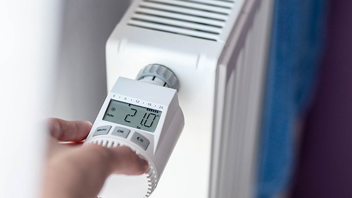 © stock.adobe.com/Daniel Jędzura Hand programmiert ein Thermostatventil an einer Heizung