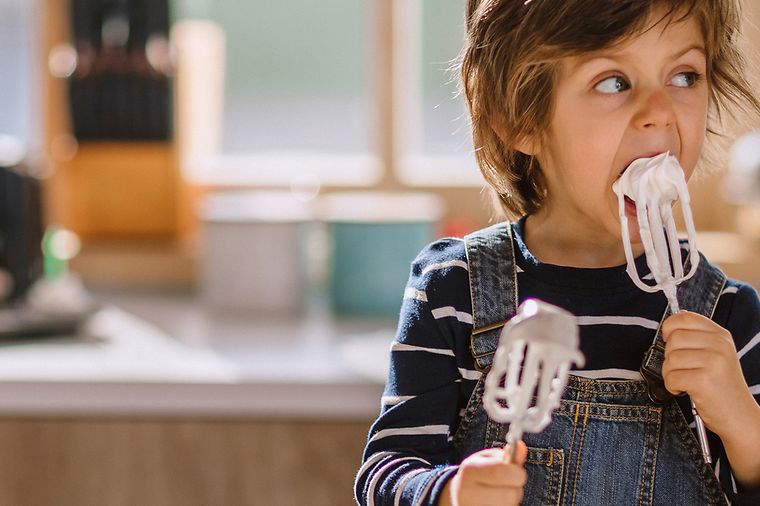 © iStock.vom/Pekic Kleiner Junge in einer Küche leckt Schlagsahne von Rührstäben ab