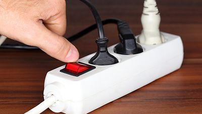 Finger legt Kippschalter an Steckerleiste um