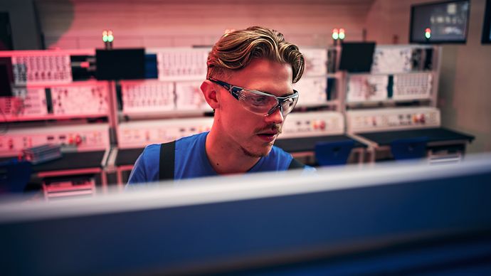In einem technischen Ausbildungsraum arbeitet eine Person konzentriert an einem Arbeitsplatz.