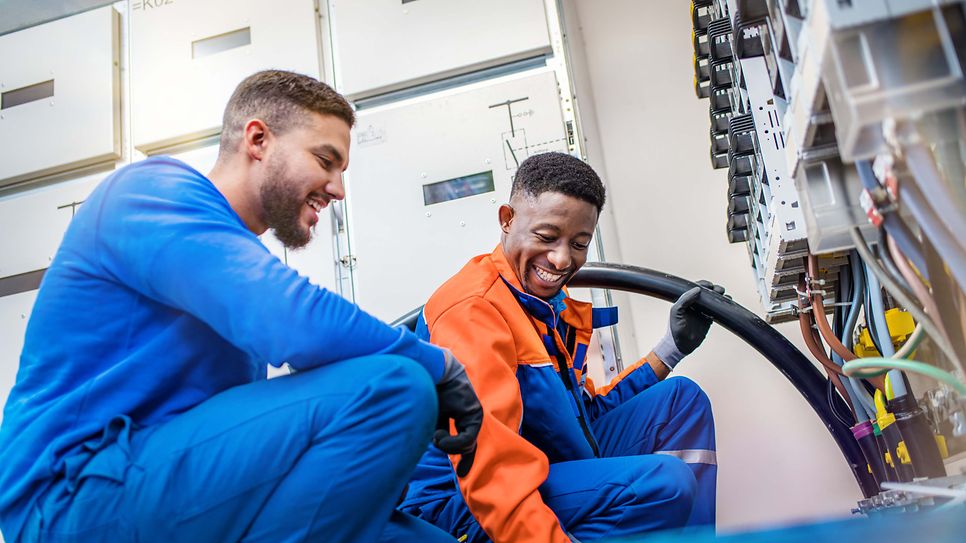 © Mainova/AndreFormer Zwei Techniker verlegen am Schaltkasten eine Starkstromleitung