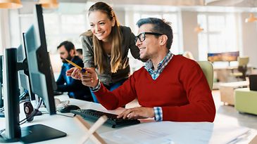 © iStock.com/Geber86 Frau und Mann schauen zusammen auf Bildschirm
