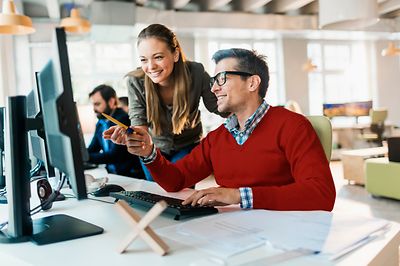 © iStock.com/Geber86 Frau und Mann schauen zusammen auf Bildschirm