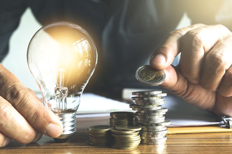 © stock.adobe.com/mintra Mann hält Glühbirne und zählt Münzgeld