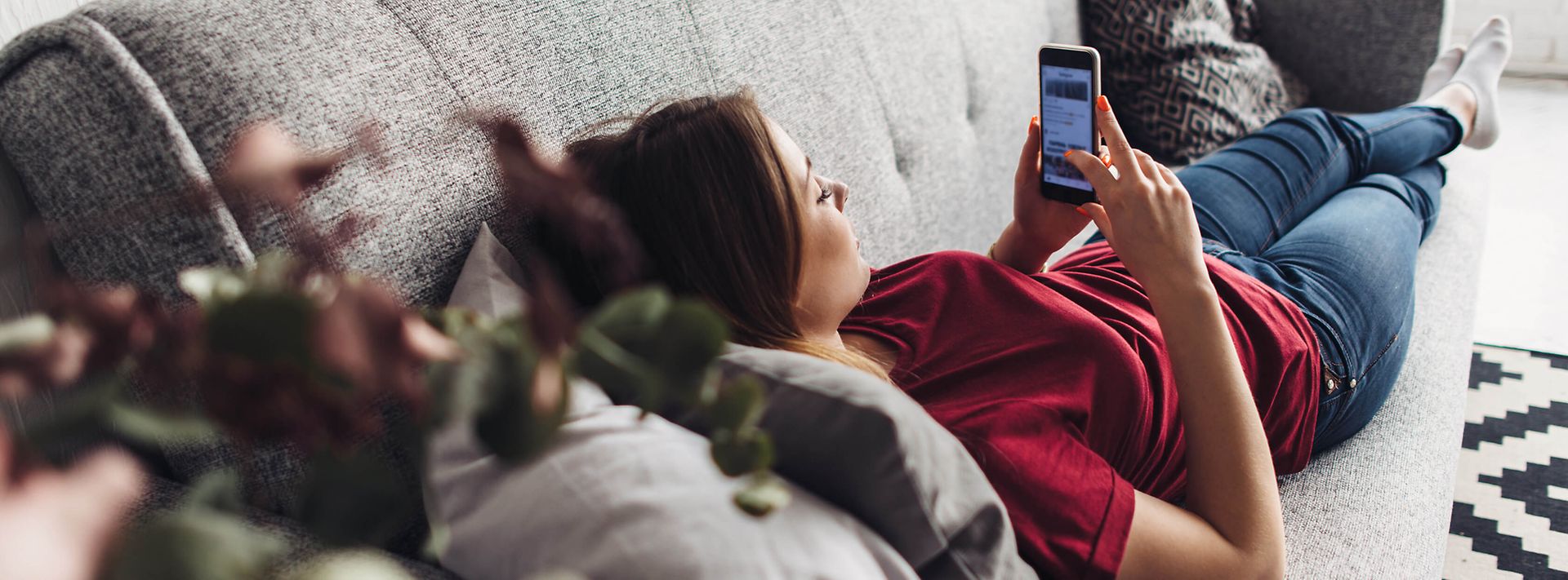 © stock.adobe.com/undrey Frau liegt mit Handy auf dem Sofa und nutzt Service-Angebot
